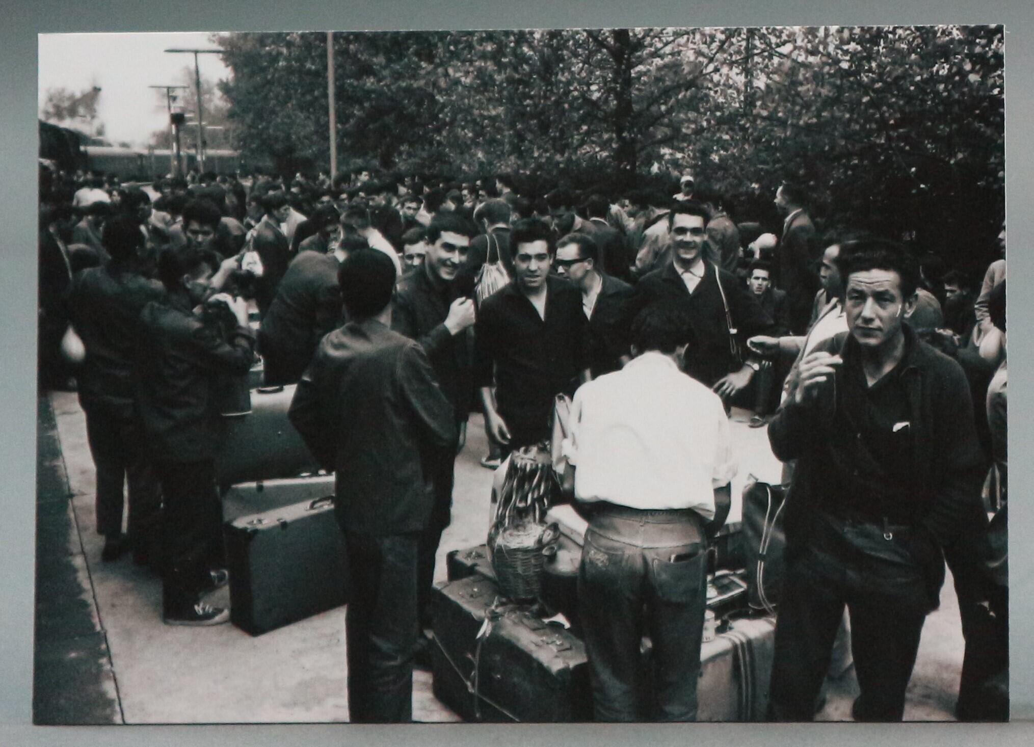 A black and white photograph. A snapshot of several men with their luggage. They are standing at Cologne-Deutz railway station.